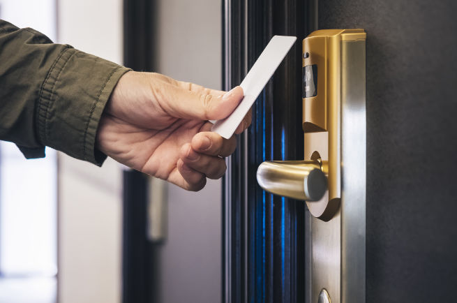 Hand holding key card up to hotel door