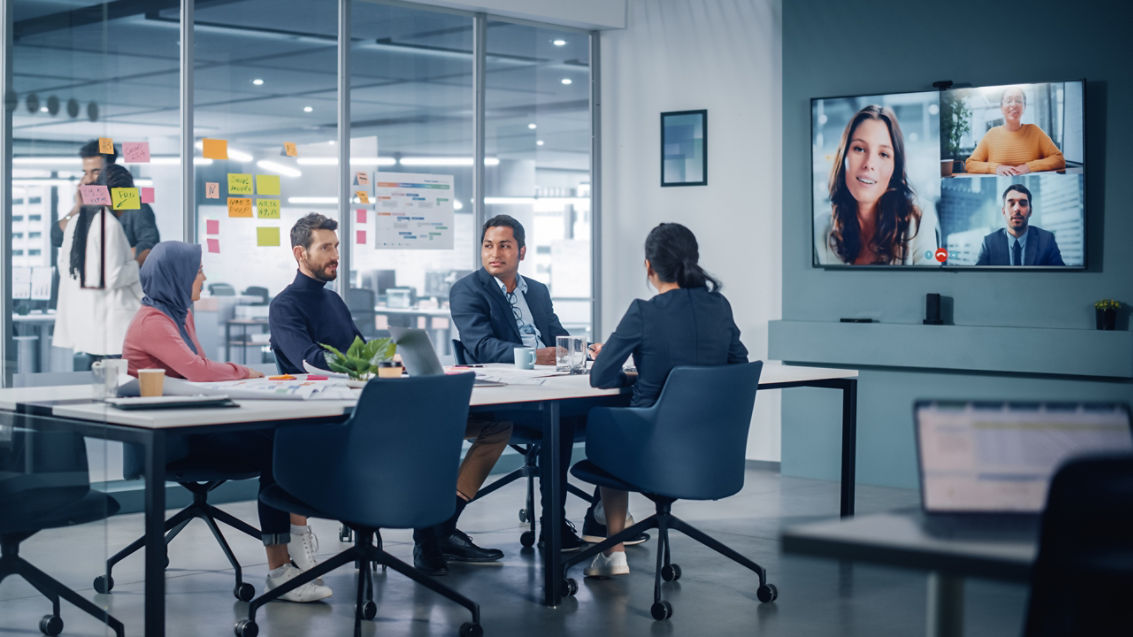 Businesspeople do Video Conference Call with Big Wall TV in Office Meeting Room. Diverse Team of Creative Entrepreneurs at Big Table have Discussion. Specialists work in Digital e-Commerce Startup