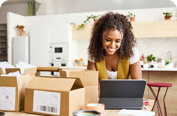 Woman looking at tablet with shipping boxes on the table