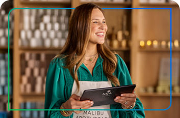 Claire, a business owner, smiles at customers while holding a tablet