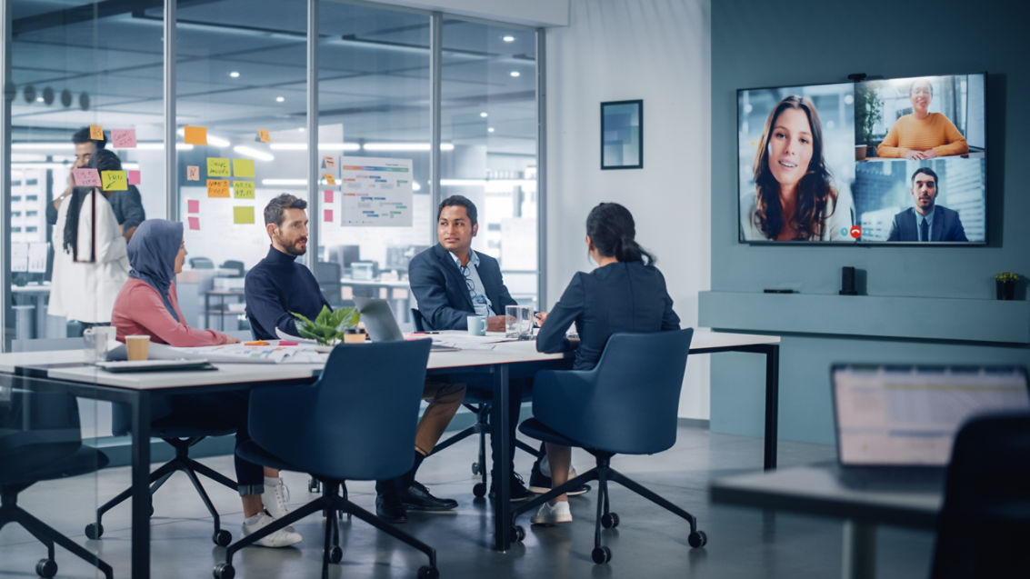 Businesspeople do Video Conference Call with Big Wall TV in Office Meeting Room. Diverse Team of Creative Entrepreneurs at Big Table have Discussion. Specialists work in Digital e-Commerce Startup