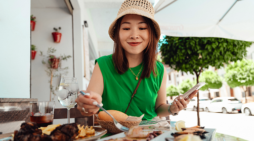 Woman wearing a hat eating at an outdoor restaurant