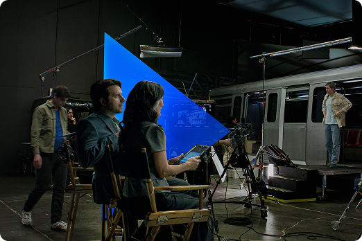 People on a set, directing film with a prop train car in the background