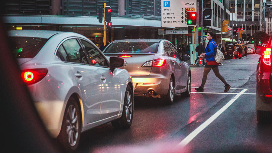 person crossing crosswalk with traffic stopped at a red light